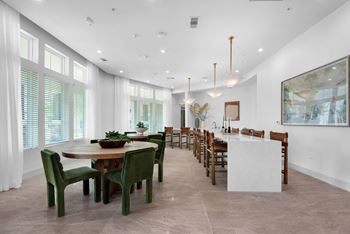 a large dining room with a long table and chairs and a kitchen with large windows at The Enclave at Deer Moss Creek, Niceville, Florida